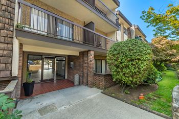 A building with a balcony and a tree in front.